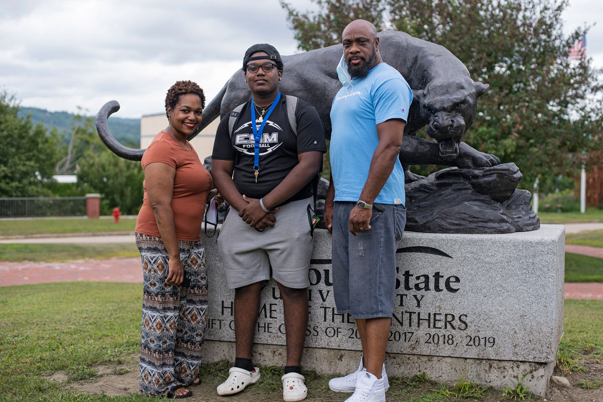 Student standing with his parents in front of the panther statue