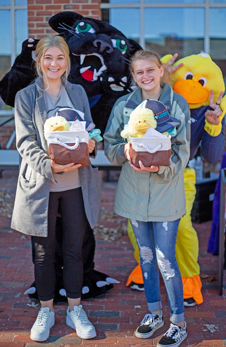 two young ladies smile holding baskets filled with ChooseLove merchandise