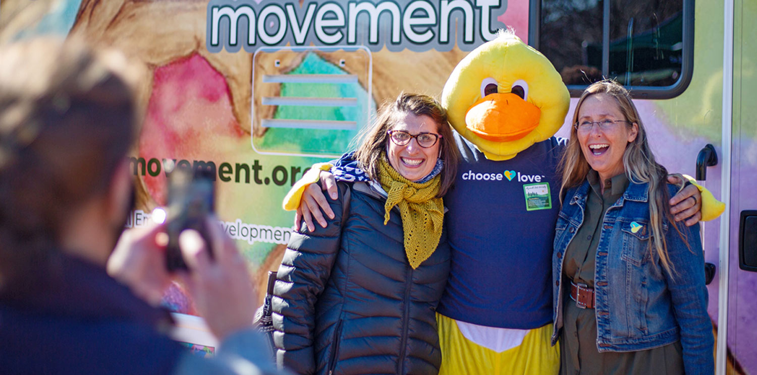 Scarlett Lewis photographed with the ChooseLove duck mascot in front of a ChooseLove Movement vehicle