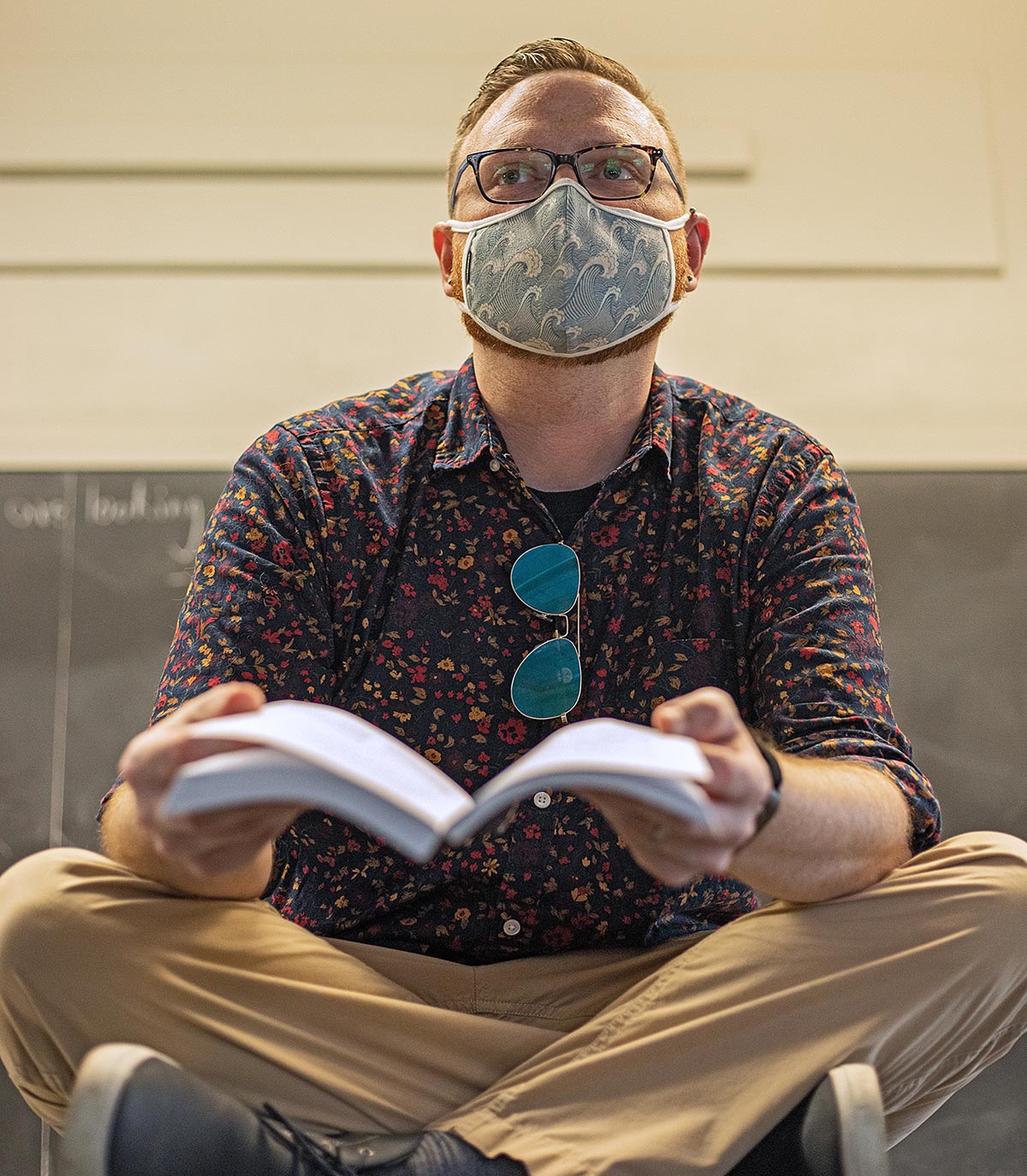Nic Helms reading a book while wearing a mask