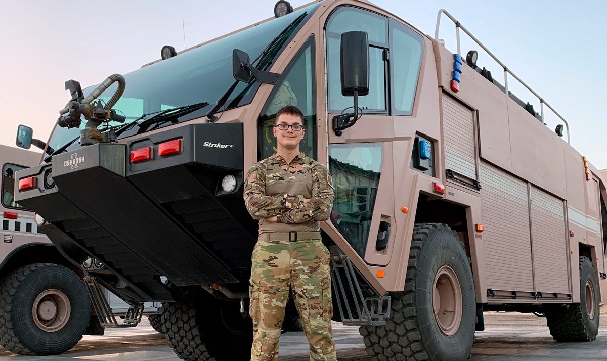Josh Chandler dressed in military uniform in front of a vehicle