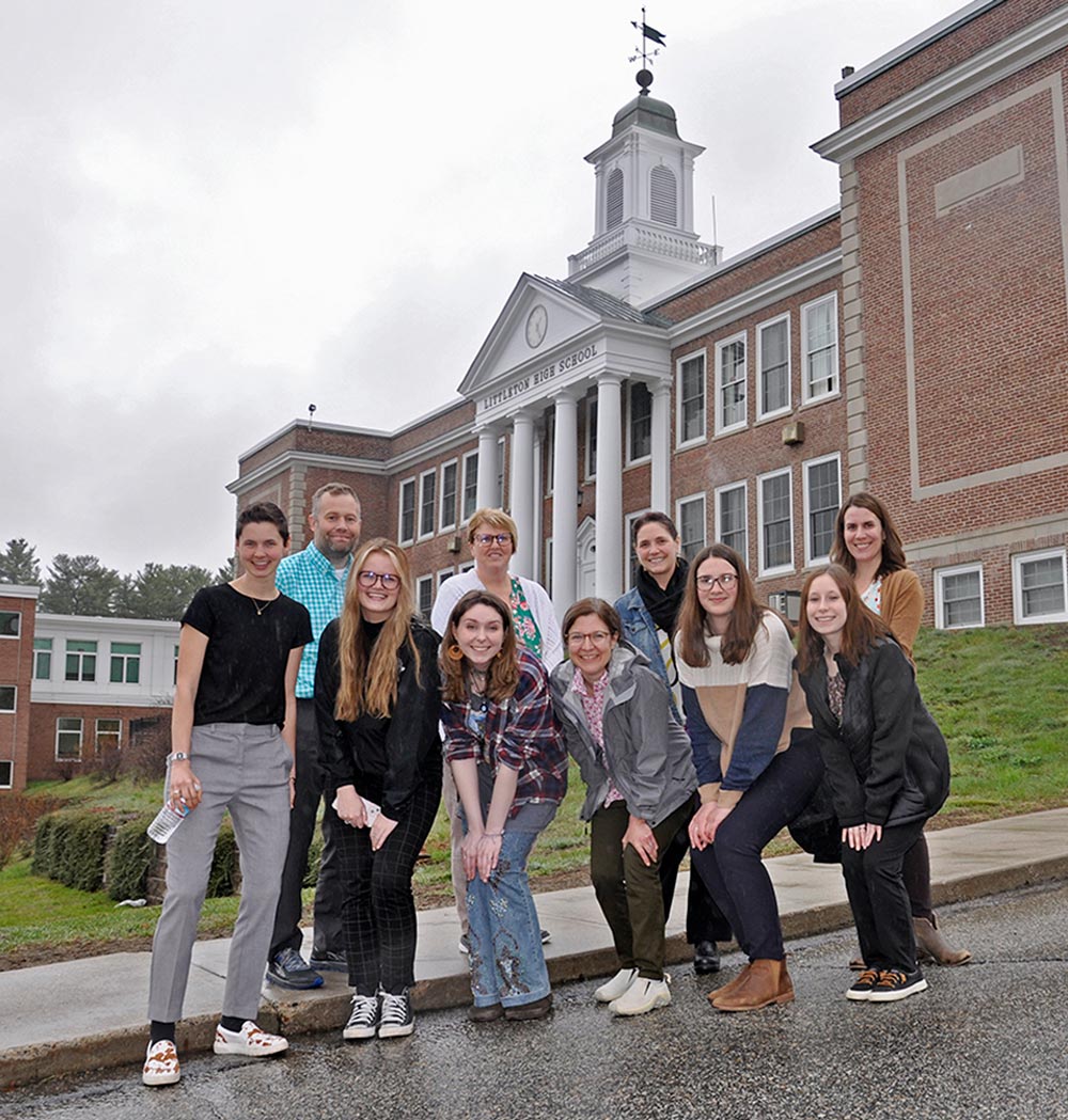 Left: Professor Brian Walker, SAU 84 Director of Student Services Kelly Noland, SAU 84 Director of Teaching and Learning Kristen Moreland, Professor Beth Fornauf. Front Row: Elena Register ’22, Brooke DeCarolis ’22, Mollie Kirwin ’22, Jennifer Malagrida, Alaina Larrabee ’22, Amanda O’Leary ’22 all stand for a photo in front of a Littleton High School building