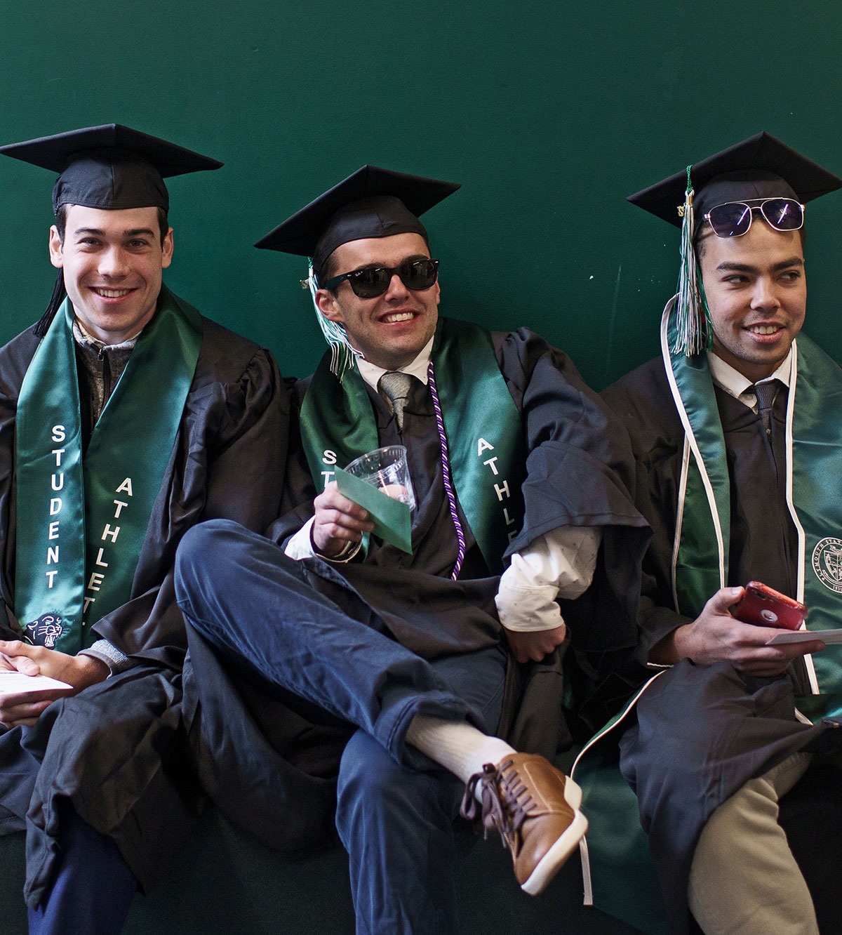 Three graduates sitting and posing for picture