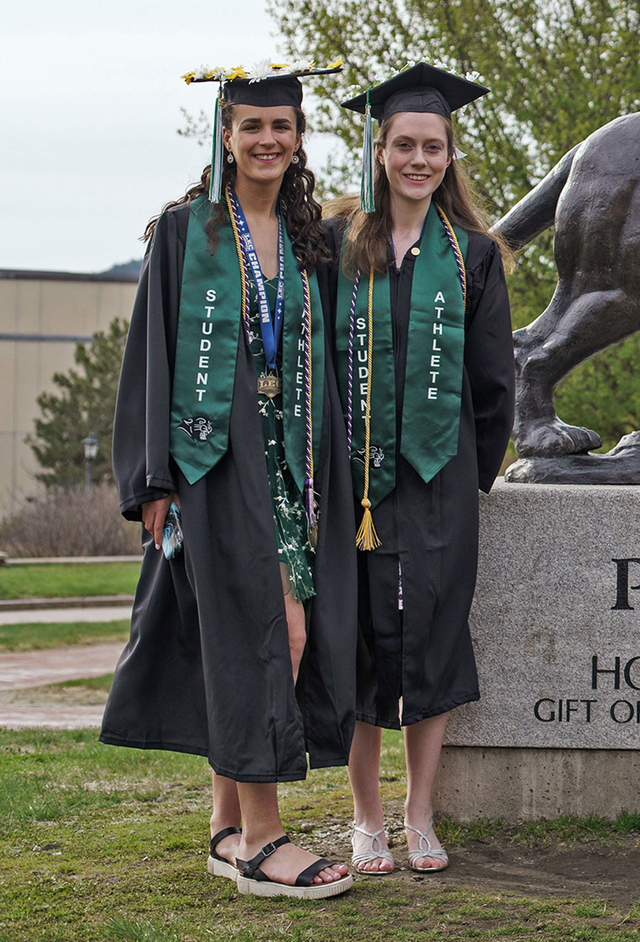 Graduates standing near school sign posing for picture