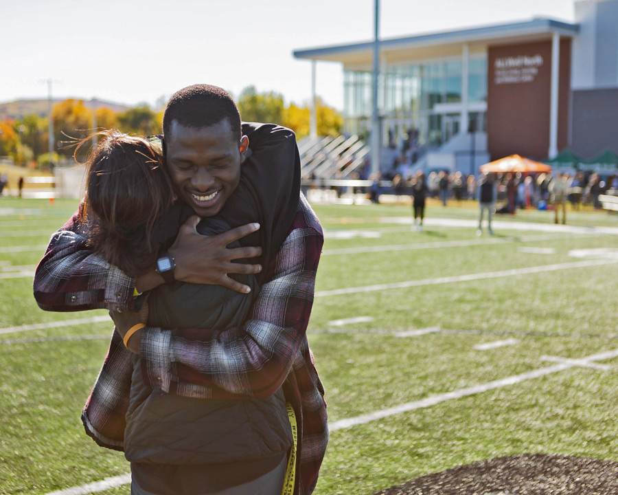 Man and woman hugging in front of the football field