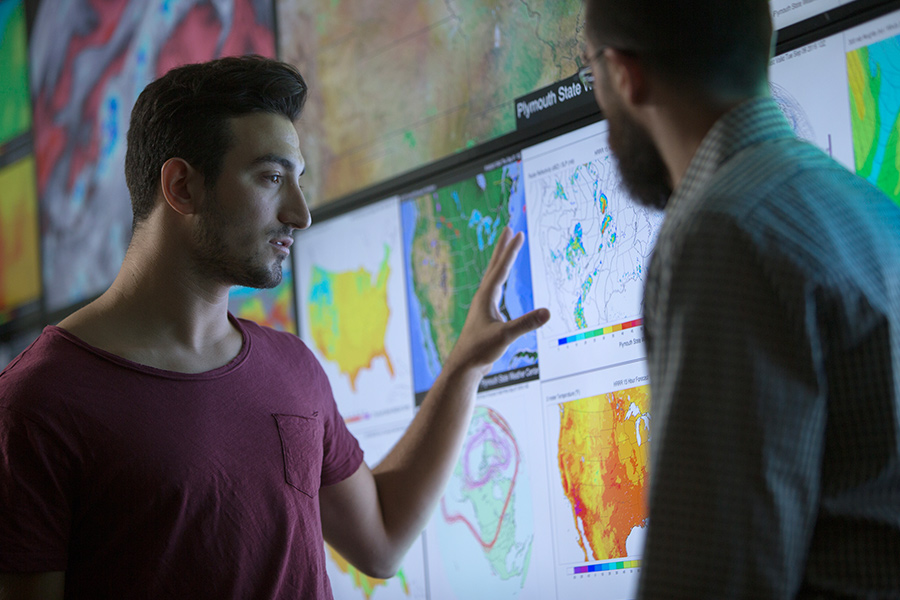 two men discuss climate data on various screens