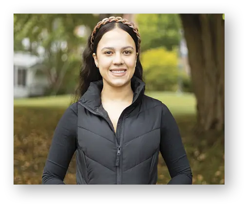 Female student in black jacket smiling outside
