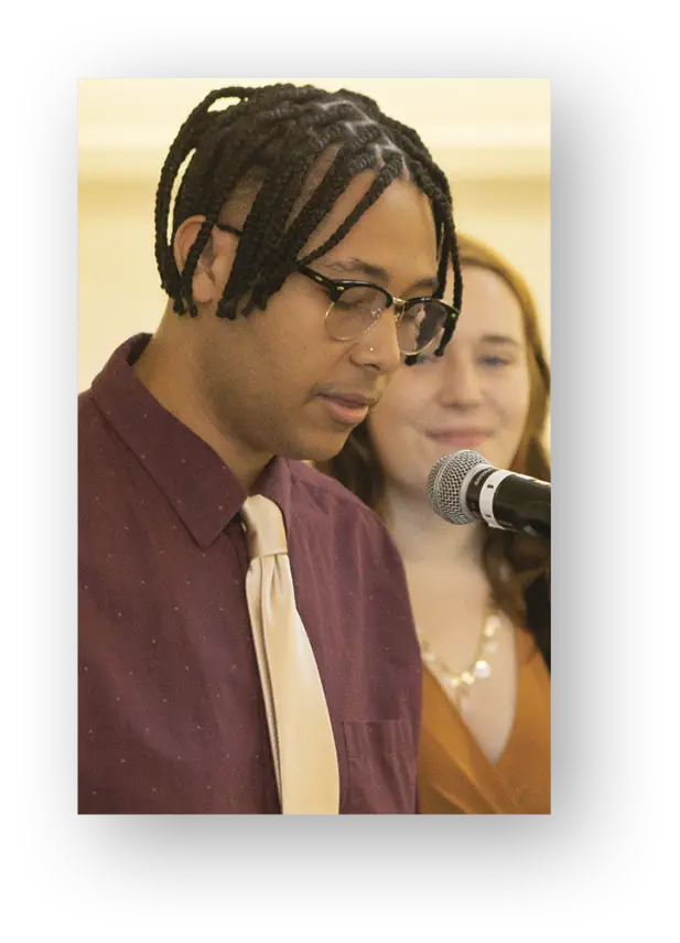 Student in maroon shirt and yellow tie speaking into microphone