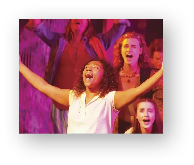 Female student in choir or play with light shining on her open arms screaming or singing while other students are behind her doing the same