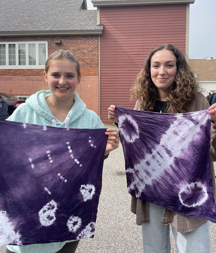 2 students holding purple tie-dyed rags