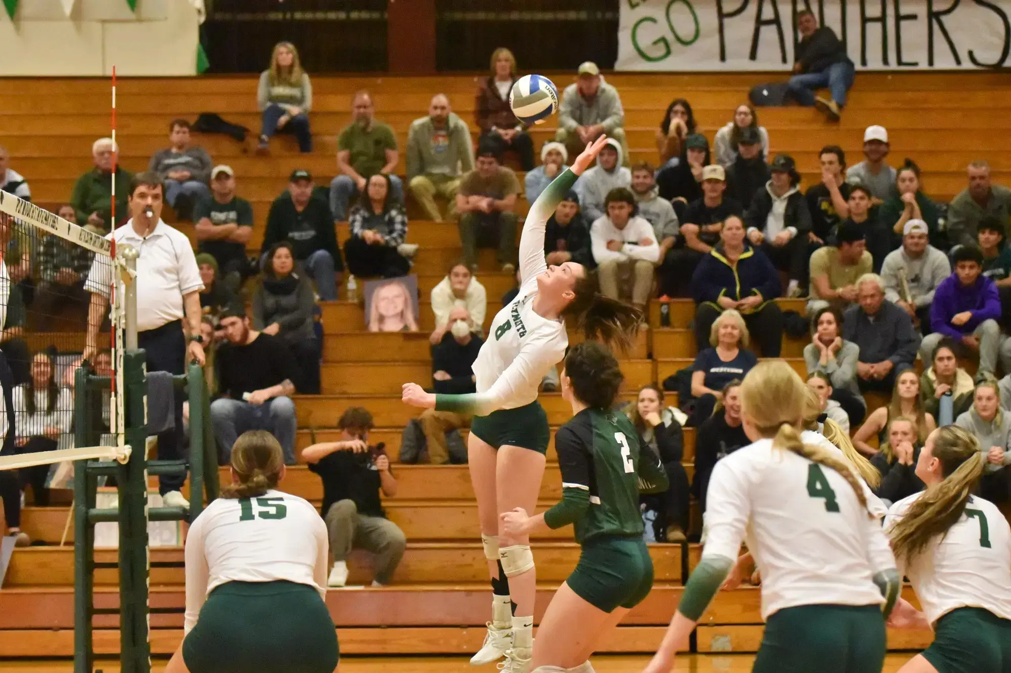 women's volleyball team member spiking ball during game