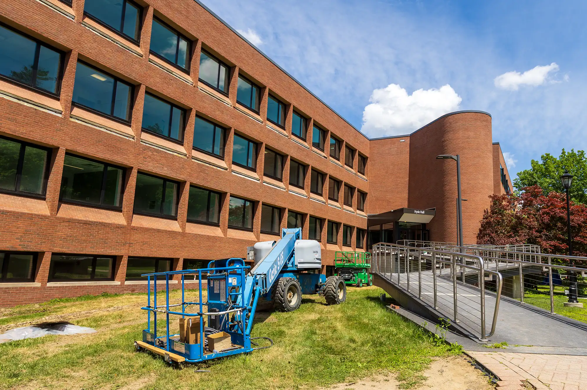 front view of Hyde Hall with two, blue and green, boom lifts parked on the lawn