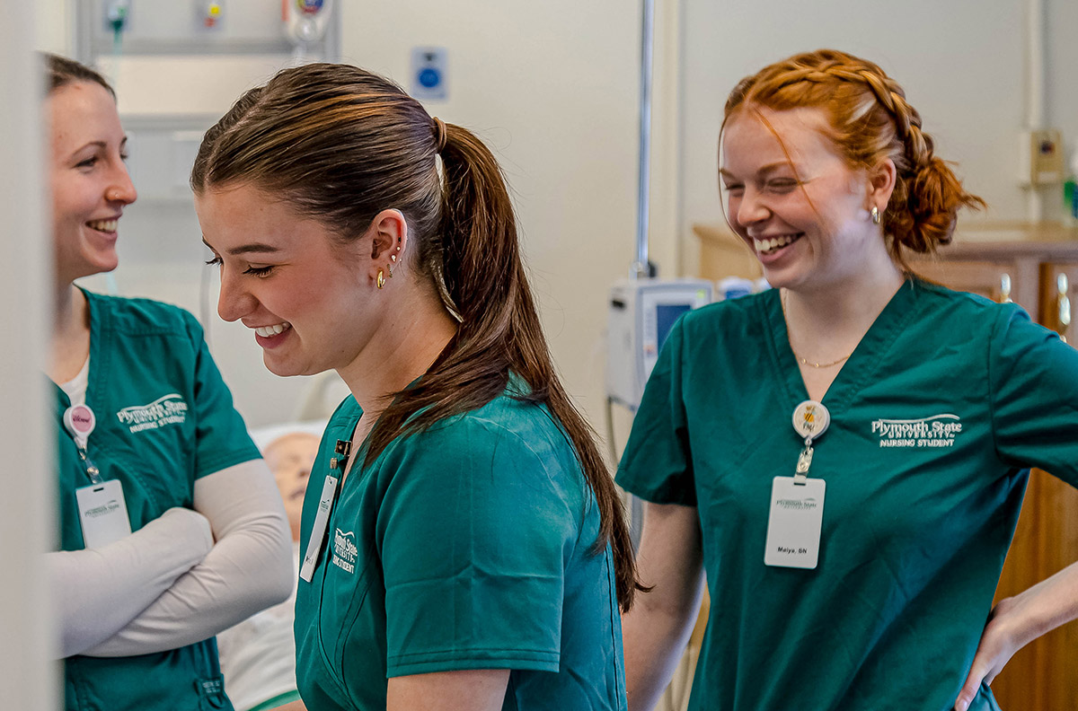 three women dressed in nurse scrubs laughing and talking to each other