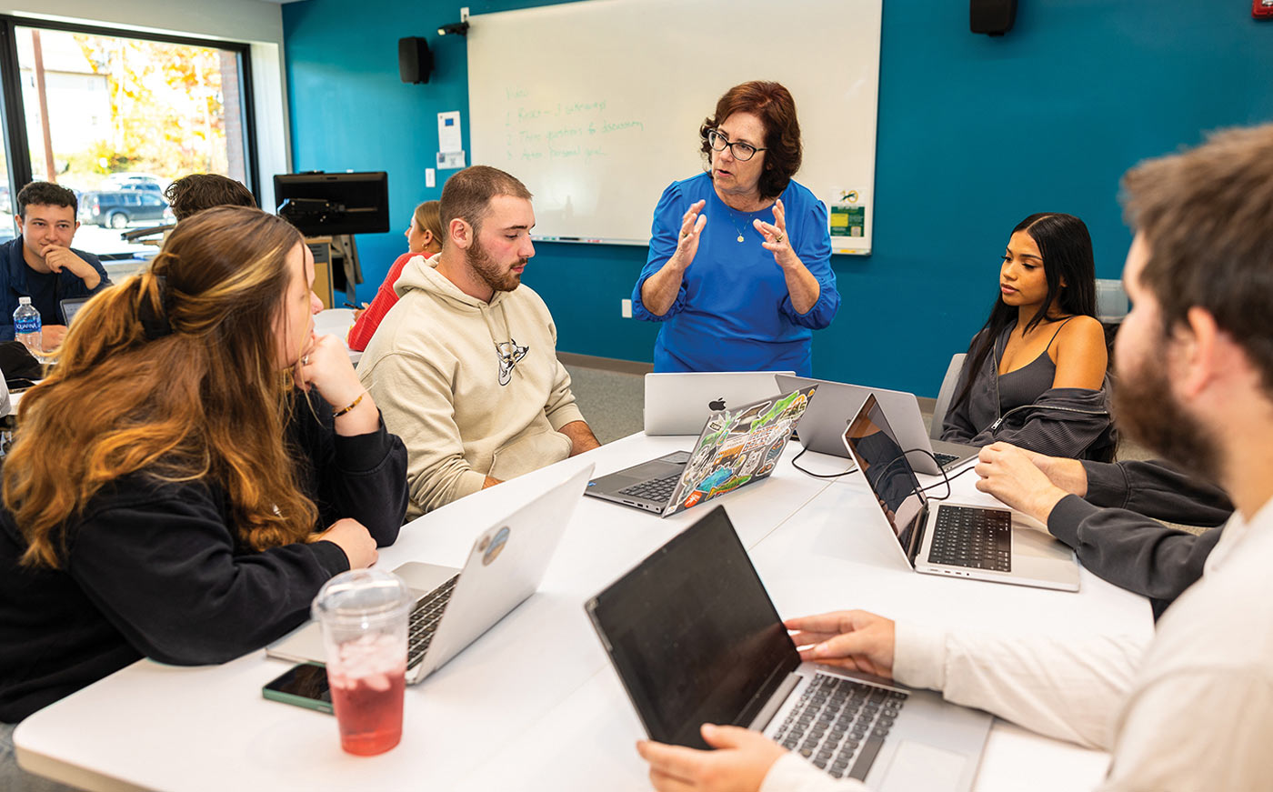 A diverse group of students and an instructor collaborate in a modern classroom setting.